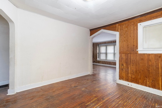 empty room featuring dark hardwood / wood-style floors and wooden walls