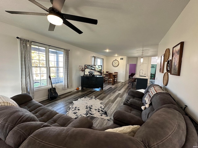 living room featuring ceiling fan, sink, and dark hardwood / wood-style floors