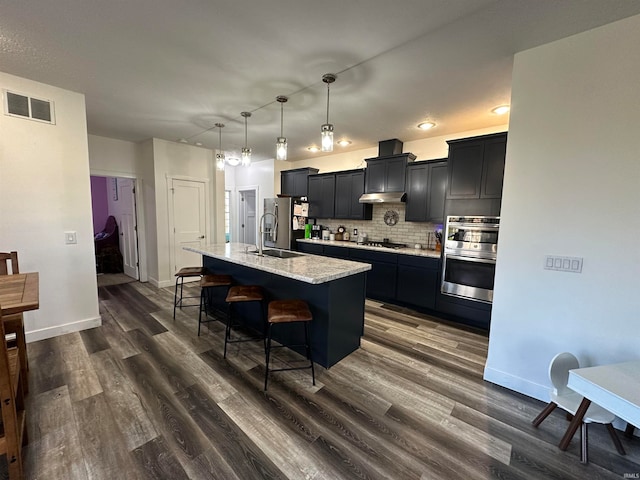 kitchen with sink, hanging light fixtures, tasteful backsplash, dark hardwood / wood-style flooring, and a kitchen island with sink