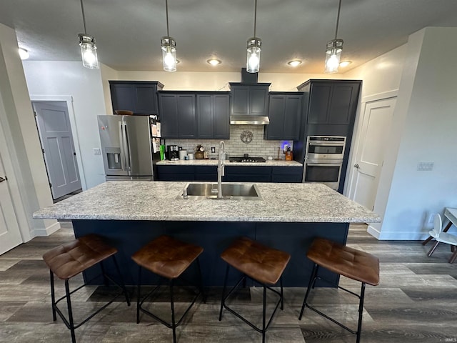 kitchen with a kitchen bar, sink, pendant lighting, and appliances with stainless steel finishes