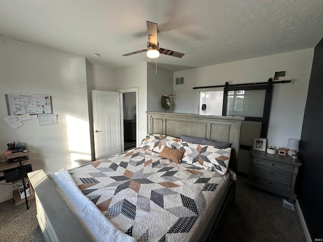 carpeted bedroom with ceiling fan, a barn door, and a textured ceiling