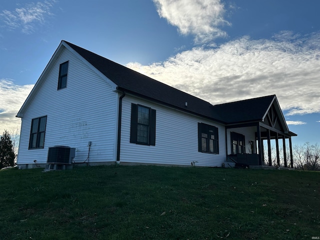 view of property exterior with a lawn and central AC