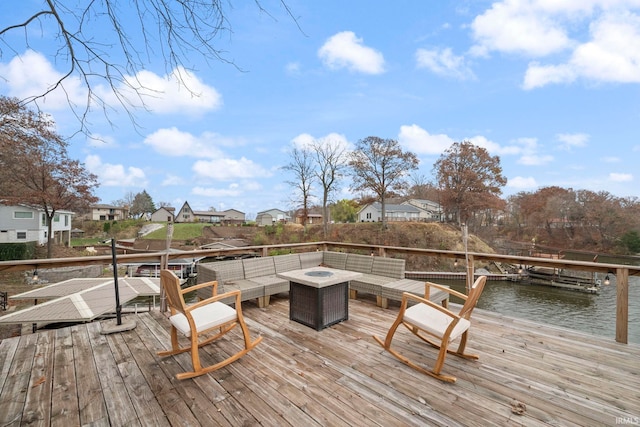 wooden deck featuring a water view and an outdoor living space with a fire pit