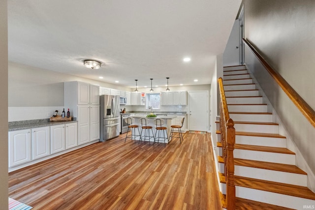 kitchen featuring white cabinetry, appliances with stainless steel finishes, a breakfast bar area, a kitchen island, and light wood-type flooring