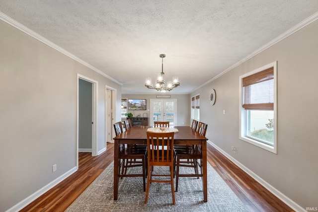 dining space with a textured ceiling, ornamental molding, dark hardwood / wood-style floors, and a notable chandelier