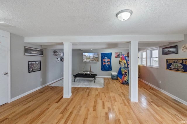 exercise room with a textured ceiling and light wood-type flooring