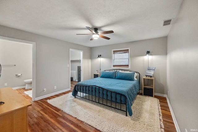 bedroom featuring ceiling fan, dark hardwood / wood-style floors, a walk in closet, and ensuite bathroom