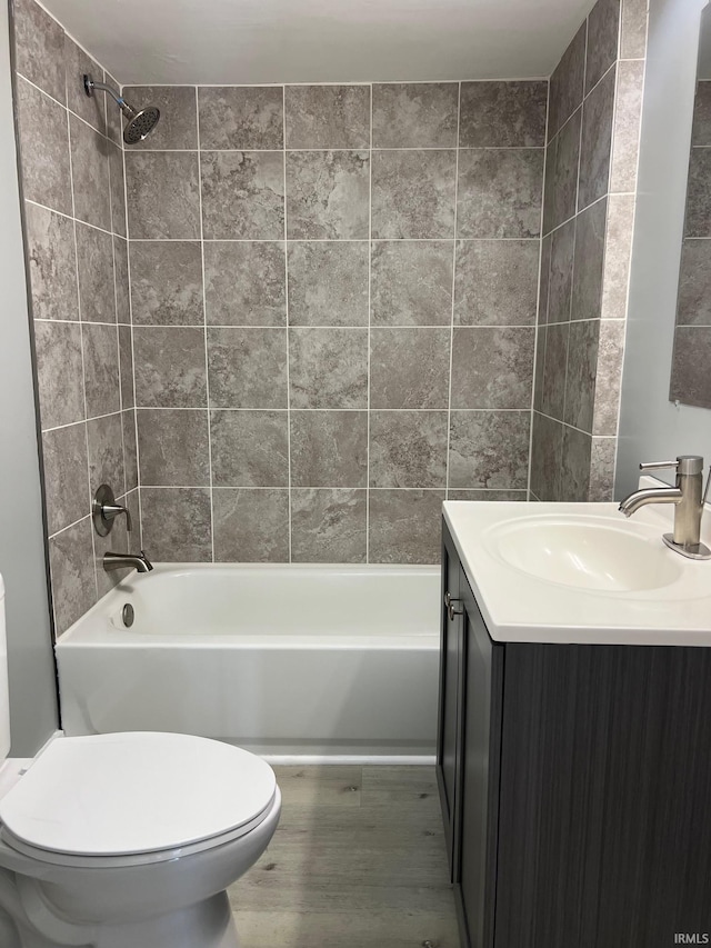 full bathroom featuring vanity, hardwood / wood-style flooring, toilet, and tiled shower / bath combo