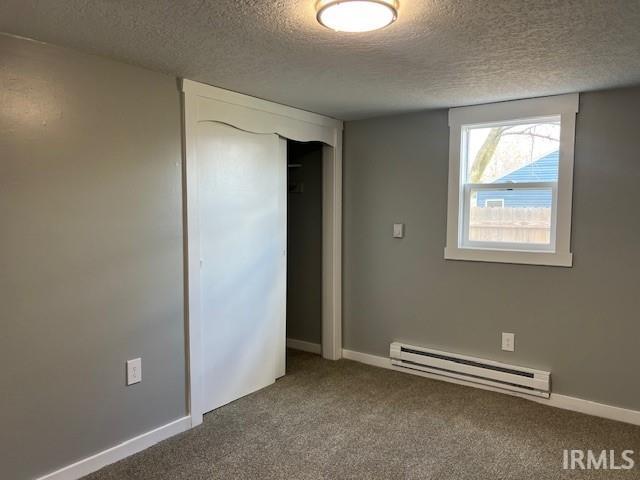 unfurnished bedroom featuring carpet, a textured ceiling, and baseboard heating