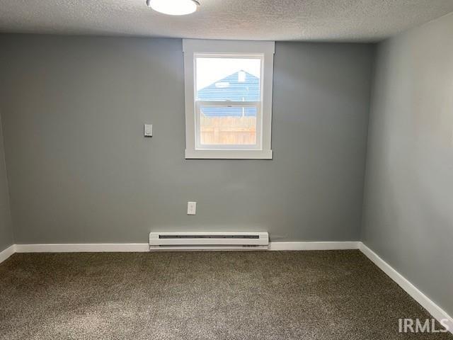 unfurnished room with carpet flooring, a textured ceiling, and baseboard heating