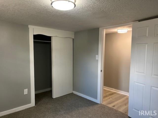 unfurnished bedroom featuring carpet, a textured ceiling, and a closet