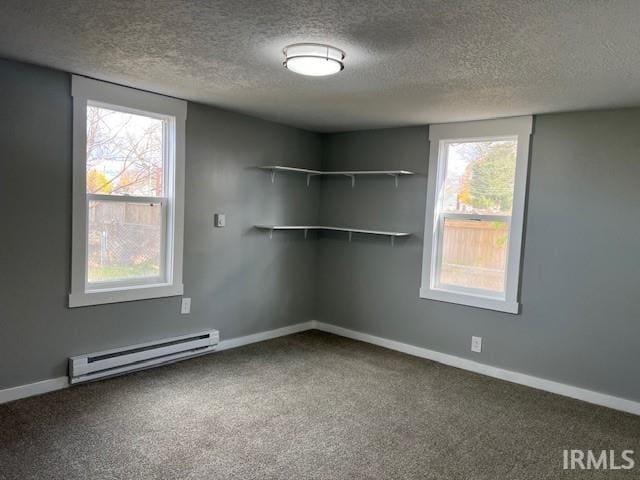 carpeted empty room with a textured ceiling and a baseboard radiator