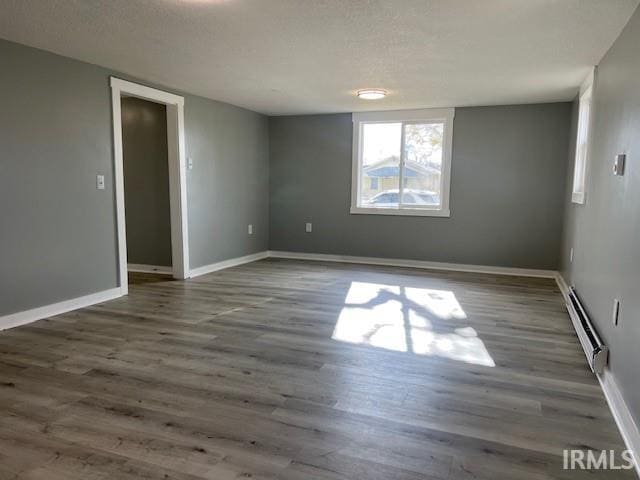 empty room featuring a textured ceiling, a baseboard radiator, and dark wood-type flooring