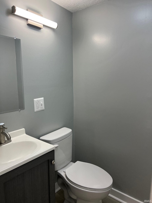 bathroom featuring vanity, toilet, and a textured ceiling