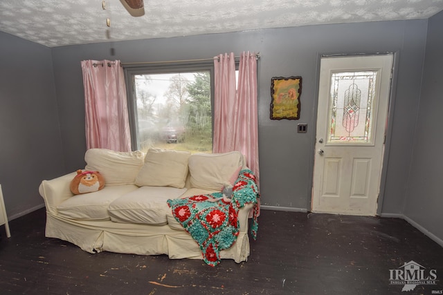 living area with a textured ceiling, ceiling fan, and dark wood-type flooring