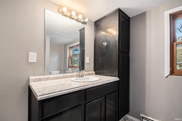 bathroom featuring toilet, vanity, and a baseboard heating unit