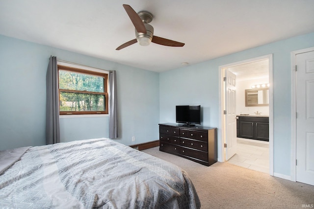 carpeted bedroom with baseboard heating, ensuite bath, ceiling fan, and sink