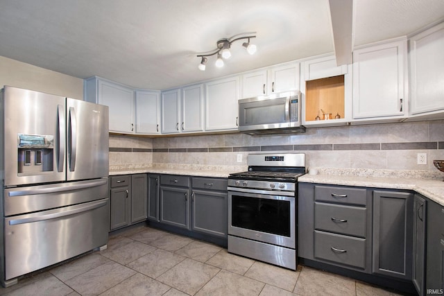 kitchen with gray cabinets, white cabinetry, decorative backsplash, and appliances with stainless steel finishes