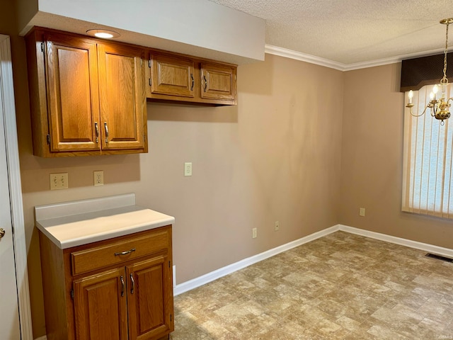 kitchen featuring ornamental molding, a textured ceiling, hanging light fixtures, and a notable chandelier