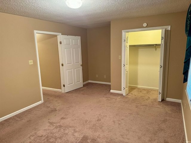 unfurnished bedroom featuring a walk in closet, a textured ceiling, light colored carpet, and a closet