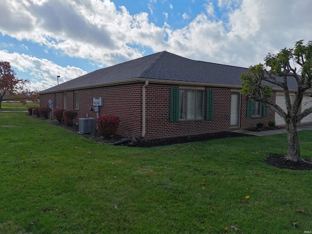 view of side of home with a lawn, a garage, and central AC