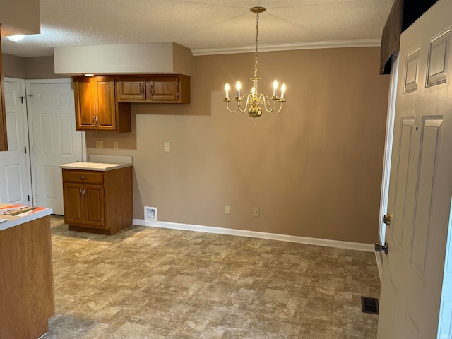 kitchen featuring pendant lighting, crown molding, a textured ceiling, and a chandelier