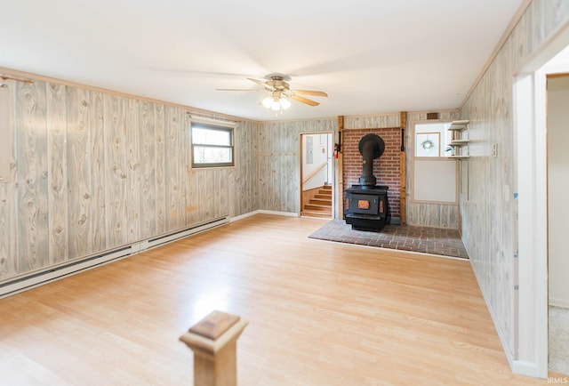 unfurnished living room with a wood stove, wood walls, and light hardwood / wood-style floors