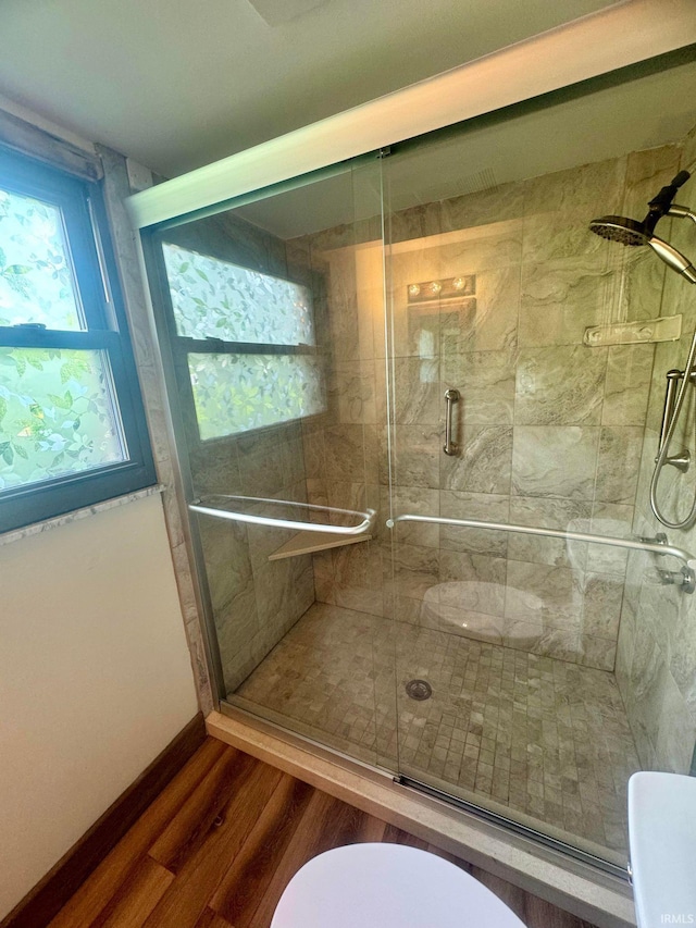 bathroom with hardwood / wood-style flooring, toilet, and an enclosed shower