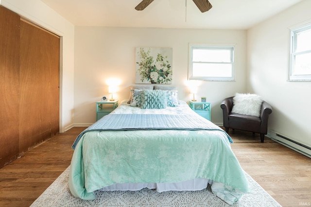 bedroom featuring ceiling fan, a closet, wood-type flooring, and multiple windows