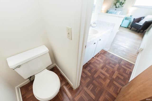 bathroom with parquet flooring, vanity, and toilet