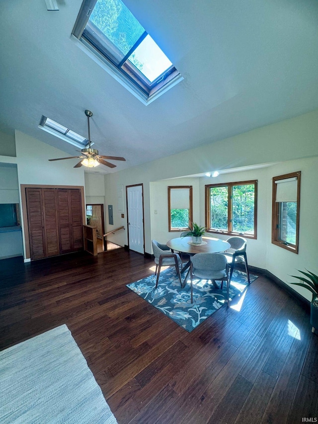 dining space featuring dark hardwood / wood-style floors, ceiling fan, and vaulted ceiling with skylight