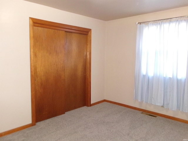 unfurnished bedroom featuring light carpet and a closet