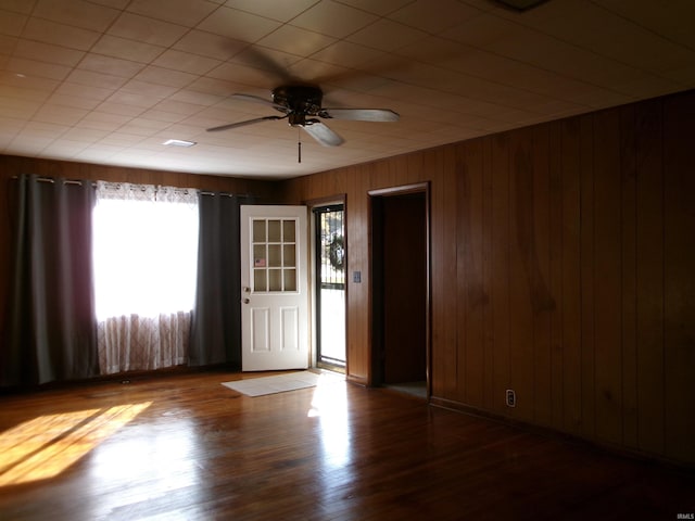 empty room featuring hardwood / wood-style flooring, ceiling fan, and wooden walls