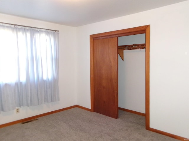 unfurnished bedroom with light carpet and a closet