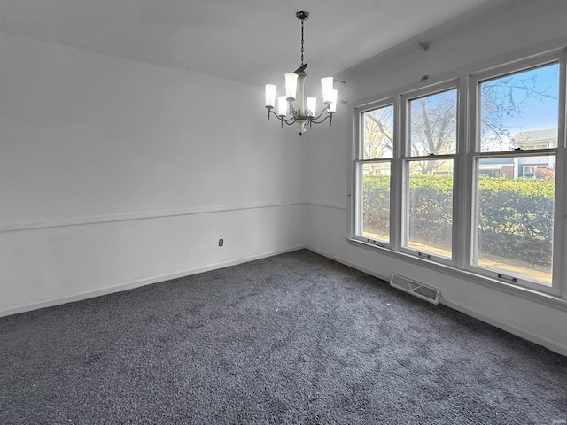 empty room with a chandelier and dark carpet