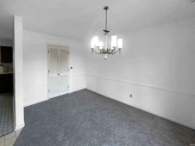 spare room featuring carpet floors and an inviting chandelier