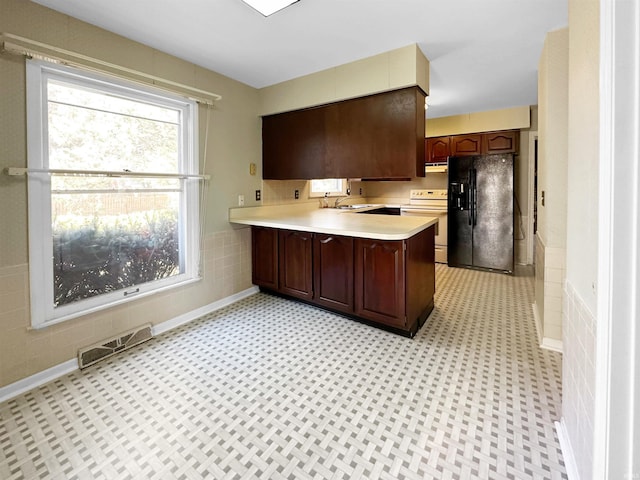 kitchen with sink, kitchen peninsula, electric stove, black fridge with ice dispenser, and dark brown cabinets