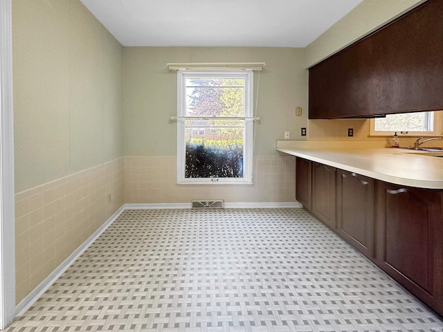 laundry area with tile walls and sink