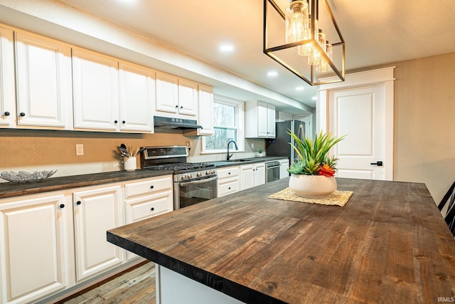 kitchen featuring white cabinetry, a kitchen island, stainless steel appliances, and wood counters