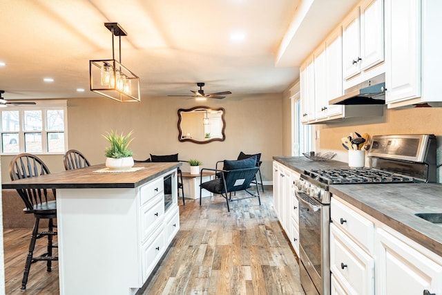 kitchen featuring a kitchen breakfast bar, stainless steel appliances, decorative light fixtures, light hardwood / wood-style flooring, and white cabinets