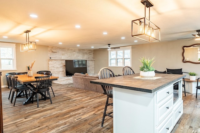 kitchen with pendant lighting, ceiling fan, white cabinetry, and hardwood / wood-style floors