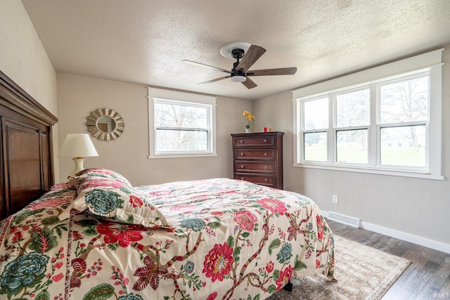 bedroom with a textured ceiling, dark hardwood / wood-style floors, and ceiling fan