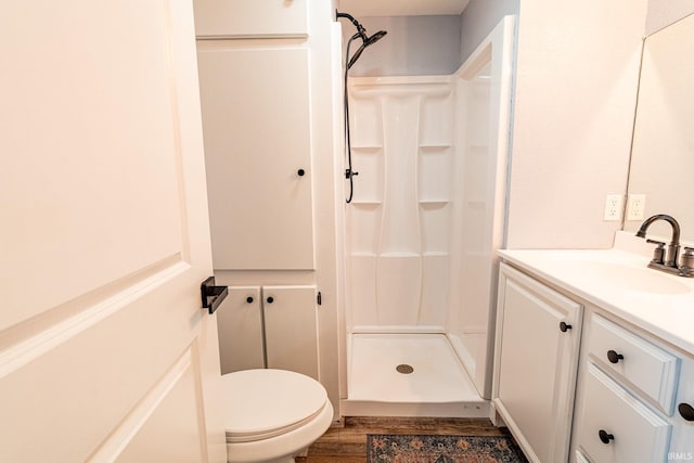 bathroom featuring wood-type flooring, vanity, toilet, and walk in shower