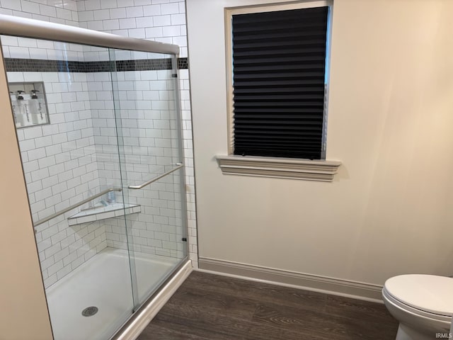 bathroom featuring toilet, a shower with shower door, and hardwood / wood-style flooring