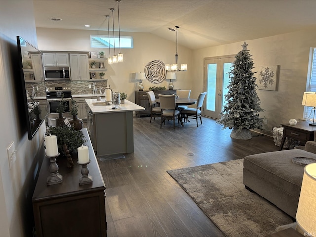 living room with a notable chandelier, sink, lofted ceiling, and dark wood-type flooring