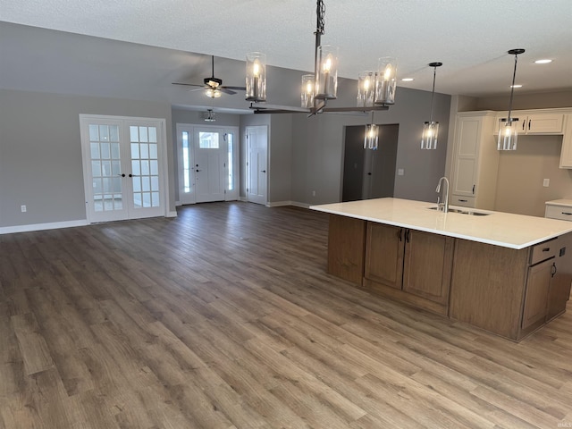 kitchen with sink, white cabinetry, decorative light fixtures, a large island with sink, and hardwood / wood-style floors