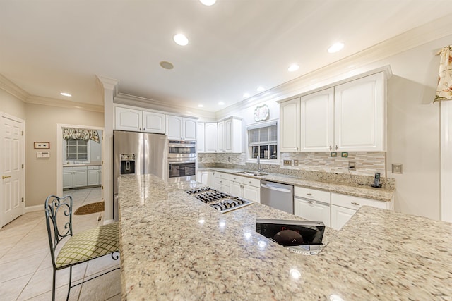 kitchen with white cabinets, stainless steel appliances, light stone counters, and sink