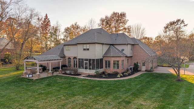 rear view of house with a lawn, a patio area, and a sunroom