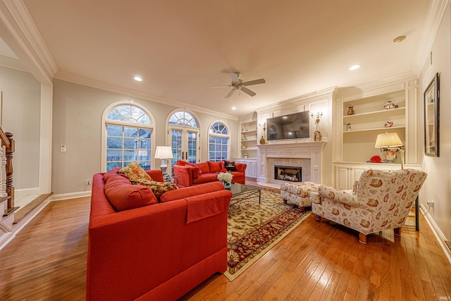 living room with hardwood / wood-style floors, crown molding, ceiling fan, and built in shelves