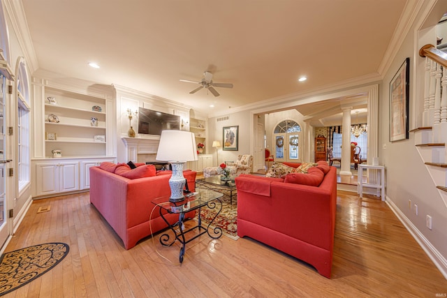 living room featuring ceiling fan with notable chandelier, built in shelves, light wood-type flooring, and ornamental molding